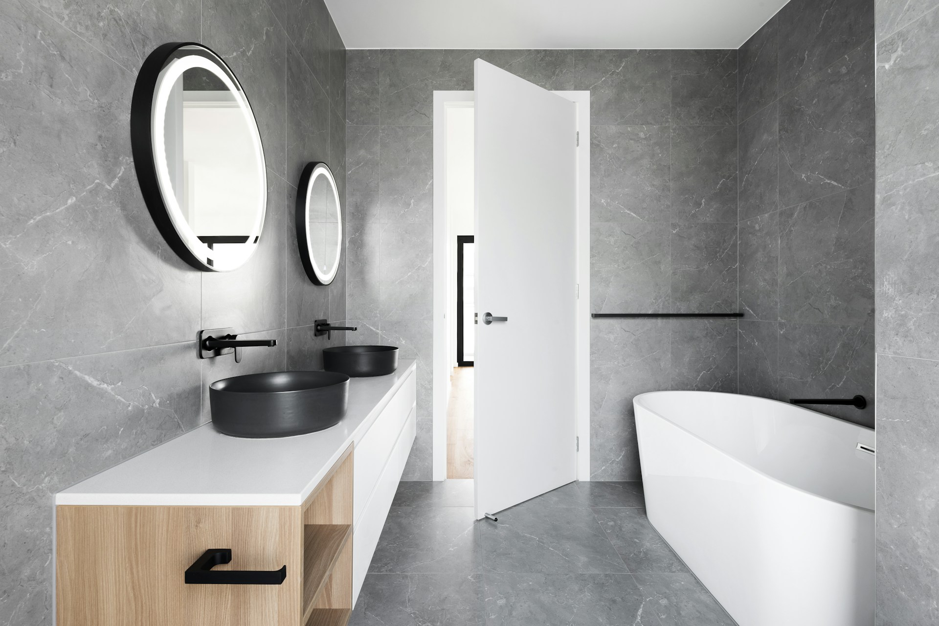 Grey marble bathroom with black basins and freestanding bath