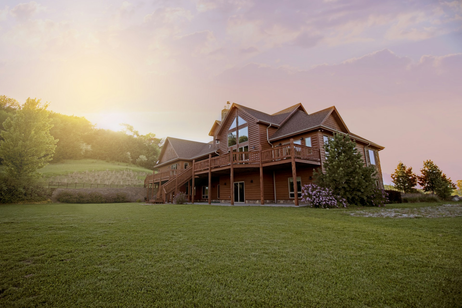 Timber lodge home with wraparound deck at sunset